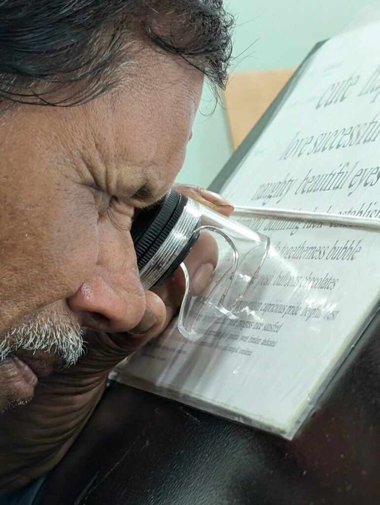 An adult man using a magnifying glass to read text on a glass surface